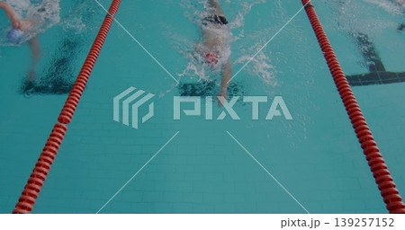 Swimming two men wearing swim caps and goggles at competition pool with red lane ropes 139257152