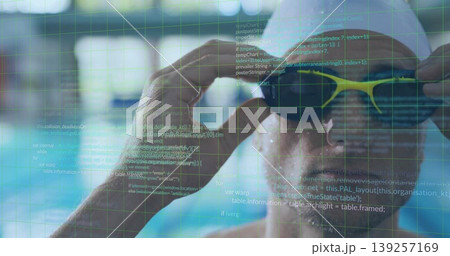 Adjusting male swimmer wearing cap tightening yellow goggles at pool lanes, code grid, copy space 139257169