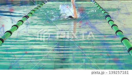 Swimming solo swimmer performing laps at lap pool, with swim cap, goggles, swimsuit and lane ropes Swimming solo swimmer performing laps at lap pool, with swim cap, goggles, swimsuit and lane ropes 139257181