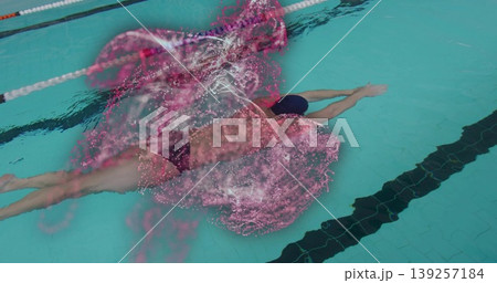 Gliding male swimmer below water surface in pool lane, with pink particles and lane divider rope Gliding male swimmer below water surface in pool lane, with pink particles and lane divider rope 139257184