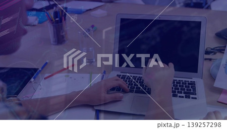 Typing office worker's hands with rolled sleeves on desk in open plan office with laptop documents Typing office worker's hands with rolled sleeves on desk in open plan office with laptop documents 139257298