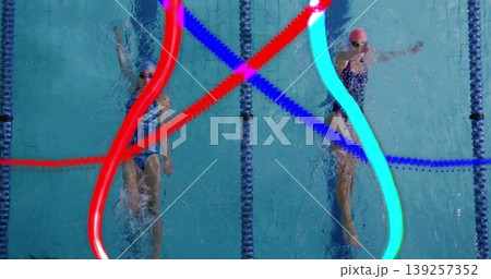 Gliding female swimmers performing backstroke at lap pool overhead, with neon trails, lane dividers 139257352