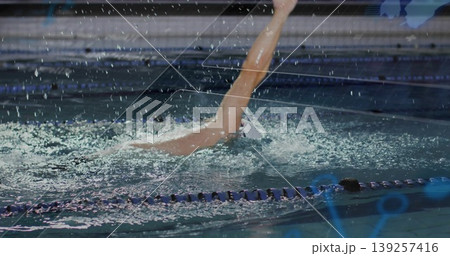 Executing backstroke swimmer propelling through lanes in training pool, with swim cap and swimsuit 139257416