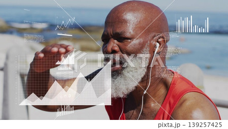 Man wearing red athletic top and earphones analyzing holographic charts on bench by sea Man wearing red athletic top and earphones analyzing holographic charts on bench by sea 139257425