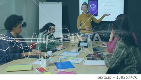 Presenting female leader gesturing at interface diagram on screen in conference room, with laptops Presenting female leader gesturing at interface diagram on screen in conference room, with laptops 139257470