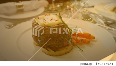 Filet mignon steak sitting in grilling net on dining table, with butter and glazed carrots Filet mignon steak sitting in grilling net on dining table, with butter and glazed carrots 139257524
