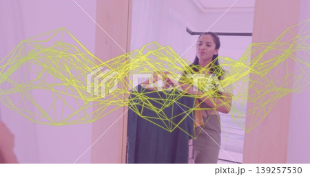 Holding wooden hanger and fabric roll, Indian woman choosing outfit in closet, wireframe overlay 139257530