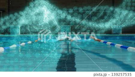Swimmer performing front crawl in pool, with cap, goggles, briefs, lane ropes, blocks and particles 139257535