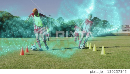 Two players wearing red white kits dribbling soccer balls through cones on grass field, with bib 139257545