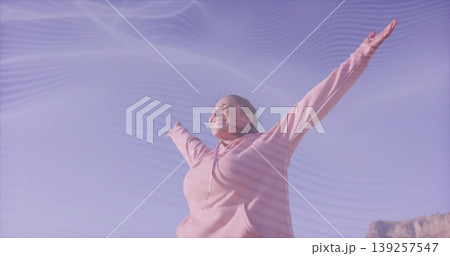 Raising arms leaning back Indian woman wearing pink hooded sweatshirt under clear blue sky Raising arms leaning back Indian woman wearing pink hooded sweatshirt under clear blue sky 139257547