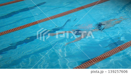 Gliding swimmer front crawling in outdoor pool, with swim cap goggles and orange lane divider ropes Gliding swimmer front crawling in outdoor pool, with swim cap goggles and orange lane divider ropes 139257606