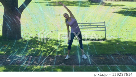 Stretching woman wearing sportswear holding water bottle on brick path in park, with metal bench Stretching woman wearing sportswear holding water bottle on brick path in park, with metal bench 139257614