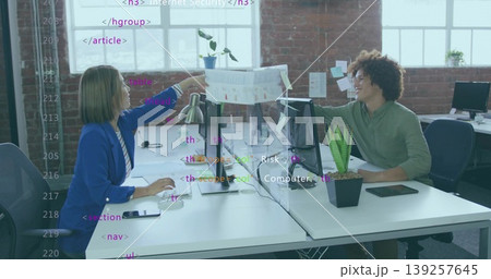 Reaching businesswoman passing printed chart to colleague over divider in office, with monitors Reaching businesswoman passing printed chart to colleague over divider in office, with monitors 139257645