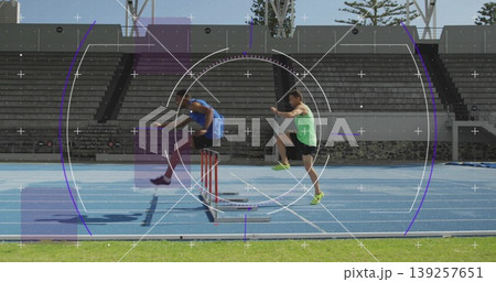 Jumping male track athletes clearing red and white hurdles on bright blue track with green turf Jumping male track athletes clearing red and white hurdles on bright blue track with green turf 139257651