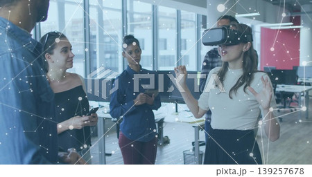 Female coworker wearing VR headset raising hands in modern open plan office, with tablet computer Female coworker wearing VR headset raising hands in modern open plan office, with tablet computer 139257678