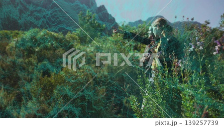Pointing couple hiking on mountain trail toward peaks, with backpacks and wildflowers, copy space 139257739