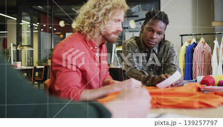 Collaborating male designers marking orange fabric in fashion studio, with pencil and pattern Collaborating male designers marking orange fabric in fashion studio, with pencil and pattern 139257797