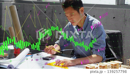 Asian man analyzing candlestick chart in design office, with blueprints on worktable, copy space Asian man analyzing candlestick chart in design office, with blueprints on worktable, copy space 139257798