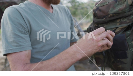 holding cartridge, bearded man wearing green V-neck shirt in woodland by camo backpack, copy space holding cartridge, bearded man wearing green V-neck shirt in woodland by camo backpack, copy space 139257801