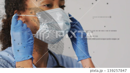Adjusting nurse securing surgical mask in studio, with blue gloves stethoscope digital overlay Adjusting nurse securing surgical mask in studio, with blue gloves stethoscope digital overlay 139257847