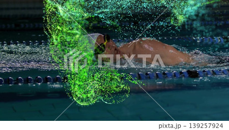 Gliding male swimmer wearing cap and goggles past lane ropes in pool, with neon digital particles 139257924