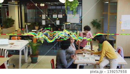 Examining four designers pointing at model at table in office, with blueprints and digital overlays Examining four designers pointing at model at table in office, with blueprints and digital overlays 139257938