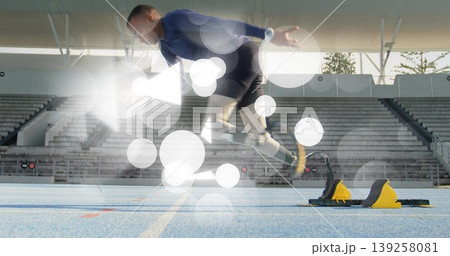Launching teen male athlete pushing off starting blocks on blue track lane, with spiked shoes 139258081