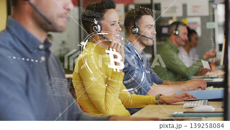 Call center agents wearing headsets working on computers in office, with Bitcoin overlay Call center agents wearing headsets working on computers in office, with Bitcoin overlay 139258084