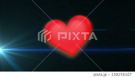 Red heart symbol glowing in dark background, with blue lens flare streaks and bright light flare 139258107