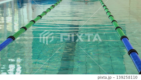 Showing central pool lane shimmering in pool interior, with green-and-blue dividers and tiled floor Showing central pool lane shimmering in pool interior, with green-and-blue dividers and tiled floor 139258110
