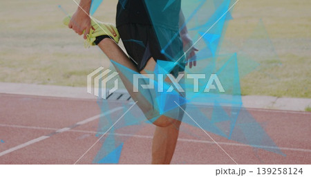 Stretching male athlete pulling foot toward buttock on red running track, neon yellow shoes Stretching male athlete pulling foot toward buttock on red running track, neon yellow shoes 139258124