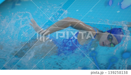 Gliding female athlete wearing blue swimsuit and cap underwater in pool, with digital overlay Gliding female athlete wearing blue swimsuit and cap underwater in pool, with digital overlay 139258138