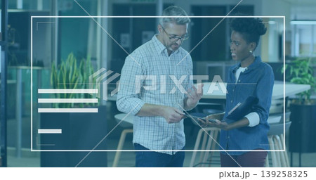 Casual attire coworkers discussing project in office lounge holding tablet and clipboard 139258325