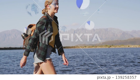 walking hiker wearing plaid shirt carrying tan backpack and metal bottle on lakeshore, copy space 139258357