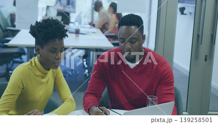 Woman in yellow turtleneck and man in red sweater writing notes in meeting area, with laptop Woman in yellow turtleneck and man in red sweater writing notes in meeting area, with laptop 139258501