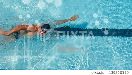 Performing front crawl male swimmer wearing swim cap and goggles over lane line, hexagon overlays 139258539