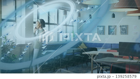 Mid adult businesswoman holding smartphone and signaling data flow in open-plan office, copy space Mid adult businesswoman holding smartphone and signaling data flow in open-plan office, copy space 139258579