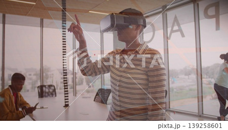 Interacting woman in striped shirt wearing VR headset reaching at conference table, with phone Interacting woman in striped shirt wearing VR headset reaching at conference table, with phone 139258601