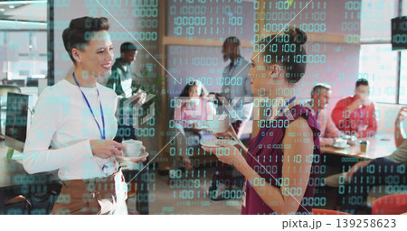 Chatting two women wearing business attire in open lounge, holding coffee cups under binary overlay 139258623