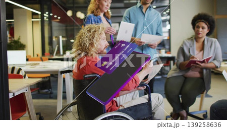 Wheelchair user in orange shirt reviewing papers in open-plan office, with purple credit card Wheelchair user in orange shirt reviewing papers in open-plan office, with purple credit card 139258636