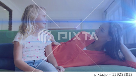 Mother and daughter reclining on green couch in living room, sharing fond gaze under sunlight flare Mother and daughter reclining on green couch in living room, sharing fond gaze under sunlight flare 139258812
