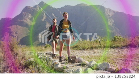 Walking couple wearing hiking boots traversing mountain trail, with logs stones shrubs lens flare Walking couple wearing hiking boots traversing mountain trail, with logs stones shrubs lens flare 139258824