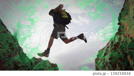 Leaping man in wide-brimmed hat, hiking boots and backpack across rugged rock gap in desert canyon Leaping man in wide-brimmed hat, hiking boots and backpack across rugged rock gap in desert canyon 139258938