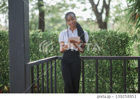 Full body portrait of young African woman holding tablet outdoors, concept of mobile productivity, remote work, digital planning and confident modern professional lifestyle. 139258951