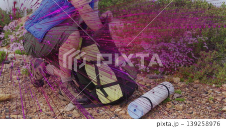 Crouching hiker securing backpack straps on rocky trail with yellow pack, pad and boots, copy space Crouching hiker securing backpack straps on rocky trail with yellow pack, pad and boots, copy space 139258976