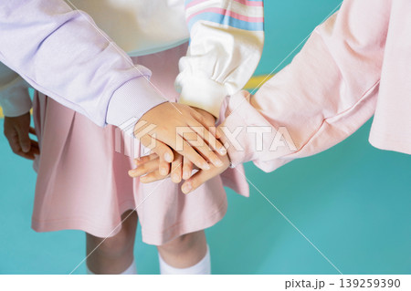 Two children are holding hands in a bright classroom. They are engaged in a group activity. Their colorful clothing adds to the fun atmosphere of the scene. Two children are holding hands in a bright classroom. They are engaged in a group activity. Their colorful clothing adds to the fun atmosphere of the scene. 139259390