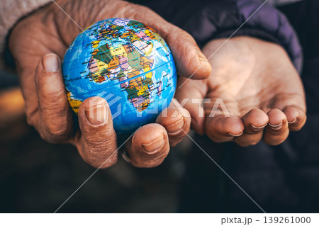 Elderly hands giving a small globe to younger hands, symbol of future, sustainability and responsibility 139261000