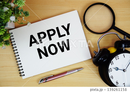 Apply Now text written on notepad with alarm clock and magnifying glass flat lay on wooden background Apply Now text written on notepad with alarm clock and magnifying glass flat lay on wooden background 139261158
