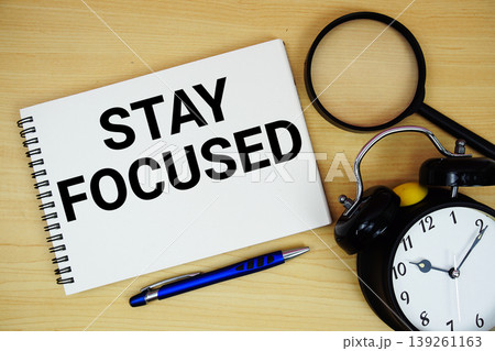 Stay Focused text written on notepad with alarm clock and magnifying glass flat lay on wooden background 139261163