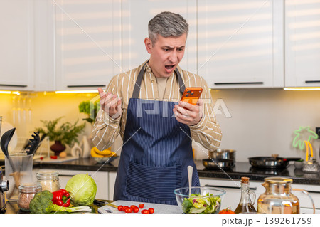 Middle-aged man reading bad smartphone message in kitchen feeling defeat failure and serious problem 139261759